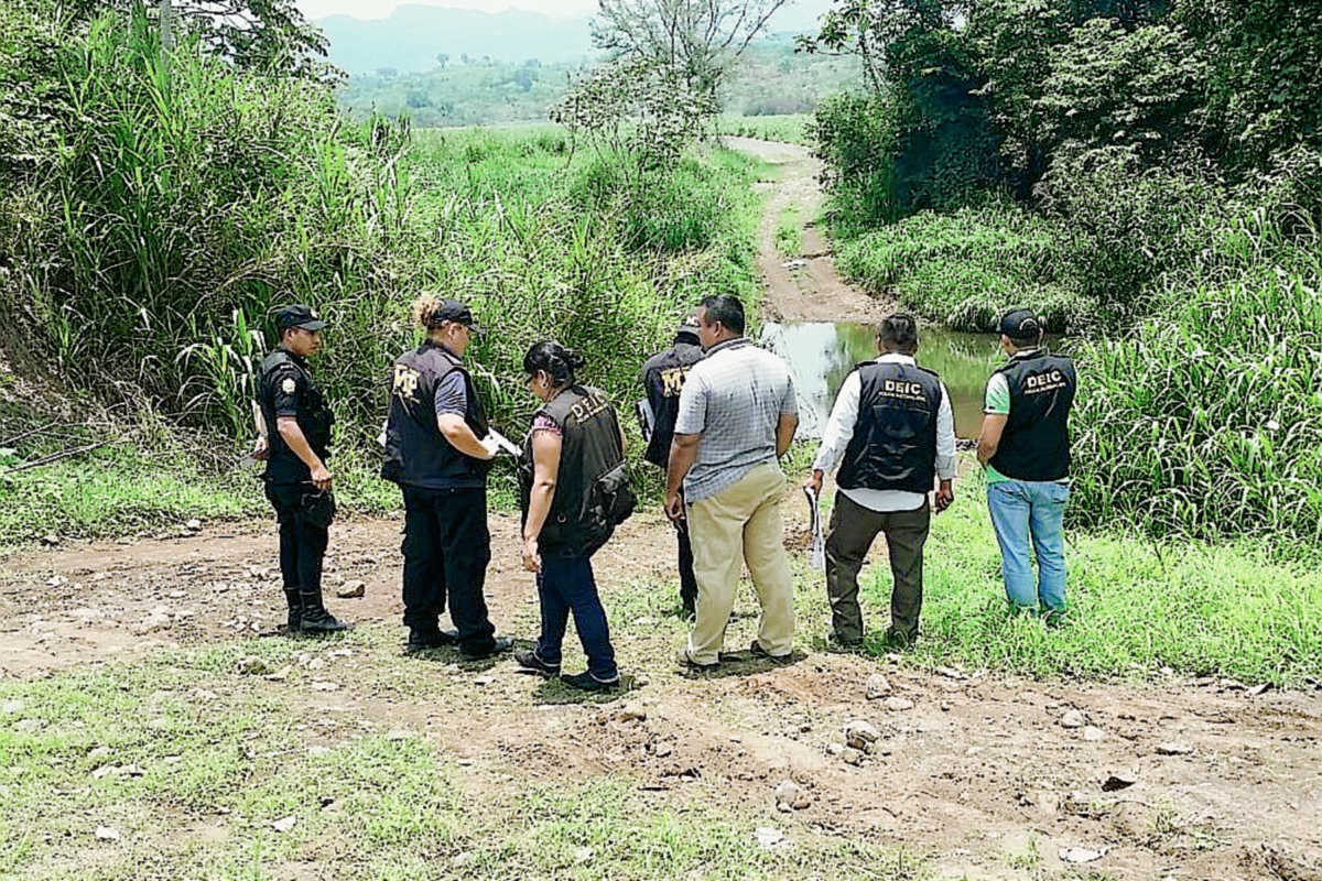 Peritos del Ministerio Público y policías buscan evidencias en el lugar donde fue hallado el cuerpo de un hombre en Guanagazapa, Escuintla. (Foto Prensa Libre: Enrique Paredes)