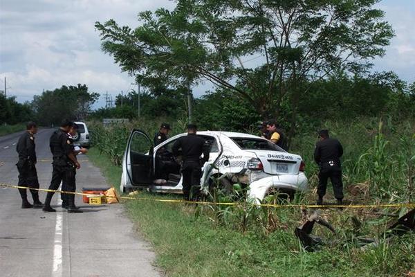 Investigadores inspeccionan el taxi baleado en el kilómetro 80 de la ruta a Puerto San José, Escuintla. (Foto Prensa Libre: Enrique Paredes) <br _mce_bogus="1"/>