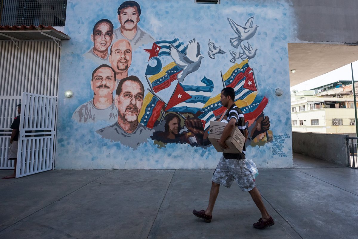 Un hombre camina cargando una caja de alimentos que compró en un programa gubernamental; el país afronta una crisis económica grave. (Foto Prensa Libre: EFE).