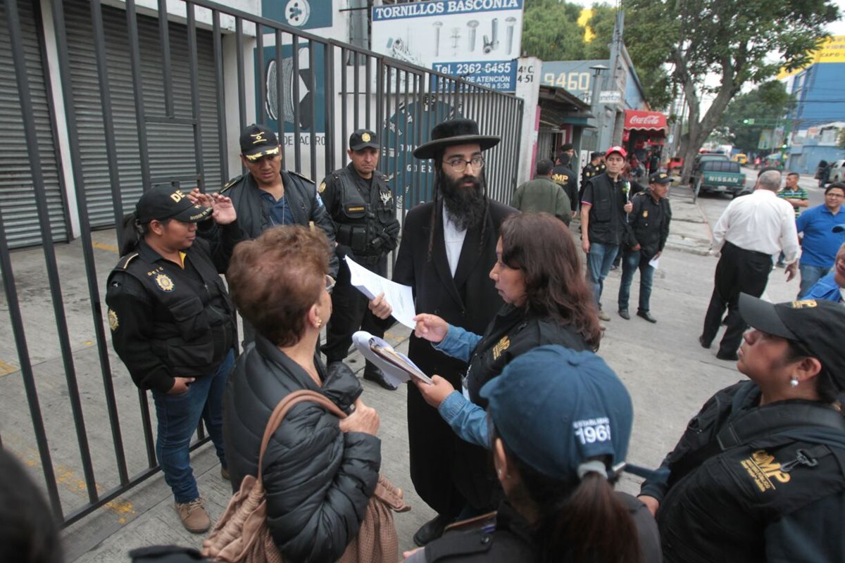 Fiscales del MP muestran la orden de allanamiento para ingresar a las viviendas de la comunidad judía en la zona 9. (Foto Prensa Libre: Erick Ávila)