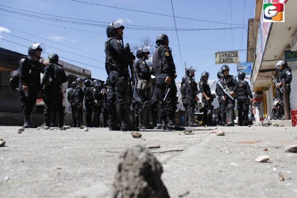 La turba lanza piedras a los agentes de la PNC que tratan de dispersar a los pobladores. (Foto Prensa Libre: Guatevisión)