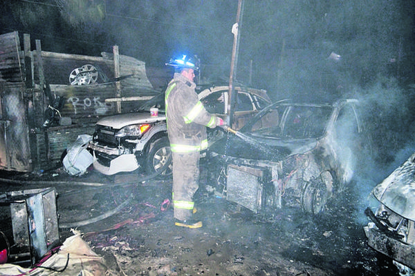 Bomberos trabajan  en apagar un incendio que consumió  ocho vehículos en la zona 4 de Mixco. (Foto Prensa Libre: CVB)