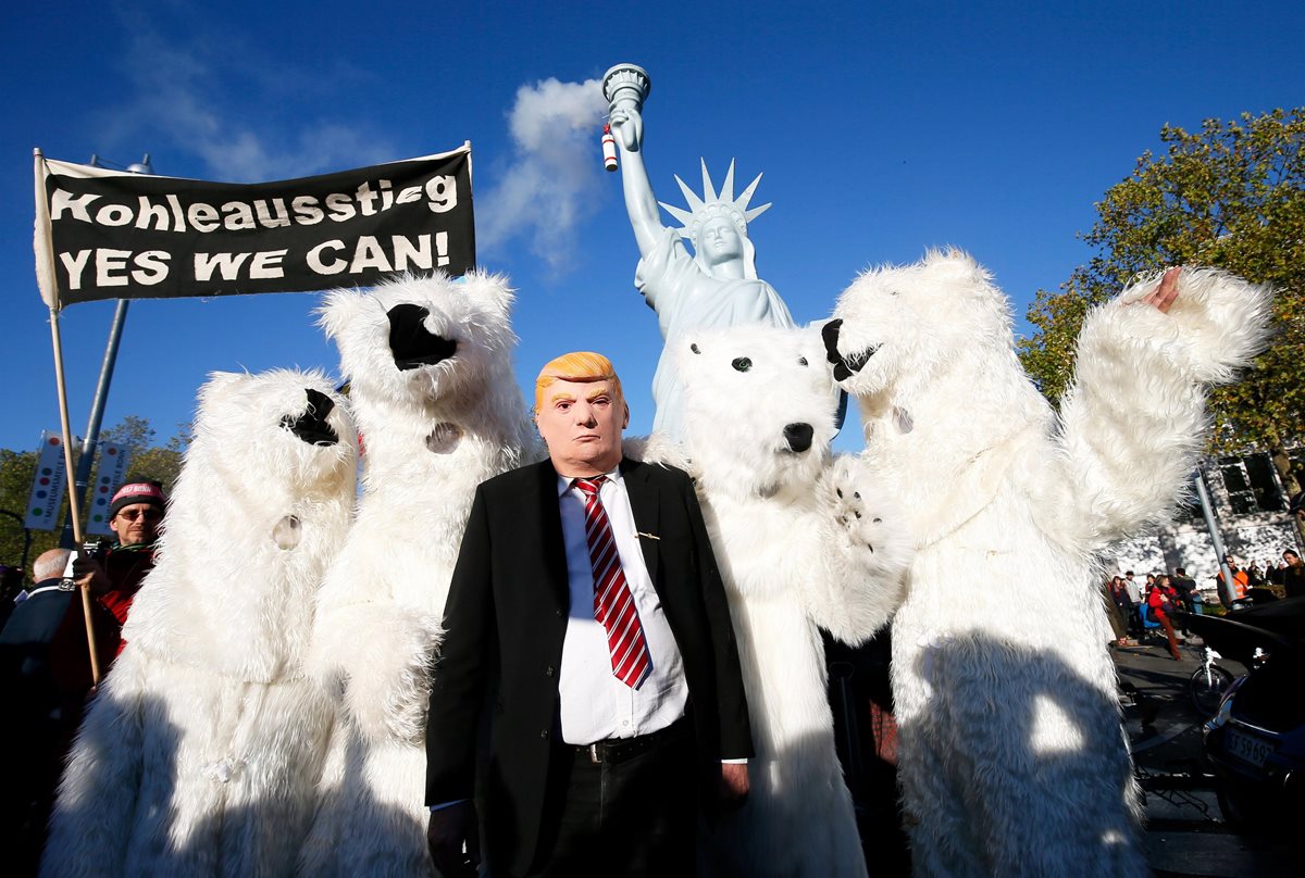 Manifestantes disfrazados con un oso polar y uno con una máscara de Turmp posan frente a una réplica de la Estatua de la Libertad.(Foto Prensa Libre:EFE).