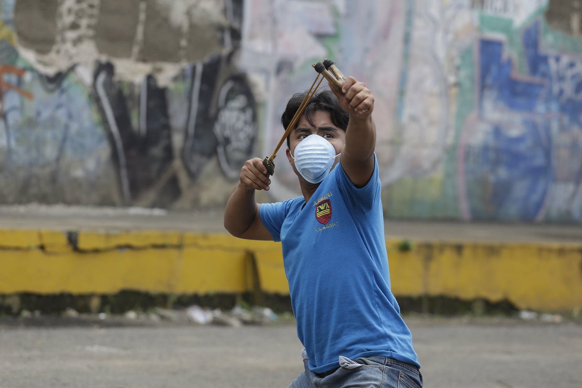 Un joven utiliza una cauchera en el pintoresco pueblo de Jinotepe se convirtió en escenario de guerra.(Foto Prensa Libre:EFE).