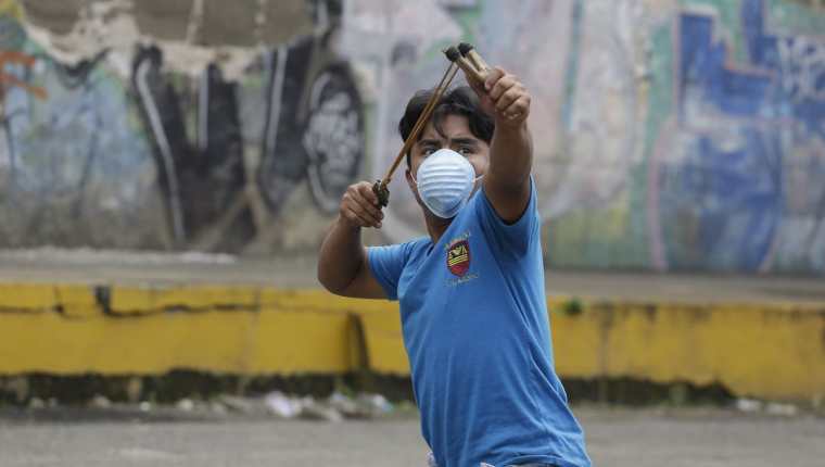 Un joven utiliza una cauchera en el pintoresco pueblo de Jinotepe se convirtió en escenario de guerra.(Foto Prensa Libre:EFE).