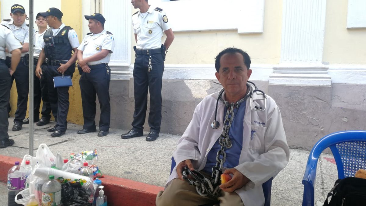 El médico José María Avelar viajó desde Mazatenango y protesta con unas cadenas, como alegoría de la esclavitud que sufren en el sistema de salud pública. (Foto Prensa Libre: Erick Ávila)