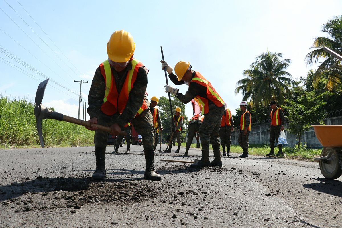 Con piochas, palas y escobas, una brigada del Cuerpo de Ingenieros del Ejército de Guatemala iniciaron las labores de bacheo en la ruta CA2 Suroccidente. (Foto Prensa Libre: Carlos Paredes)