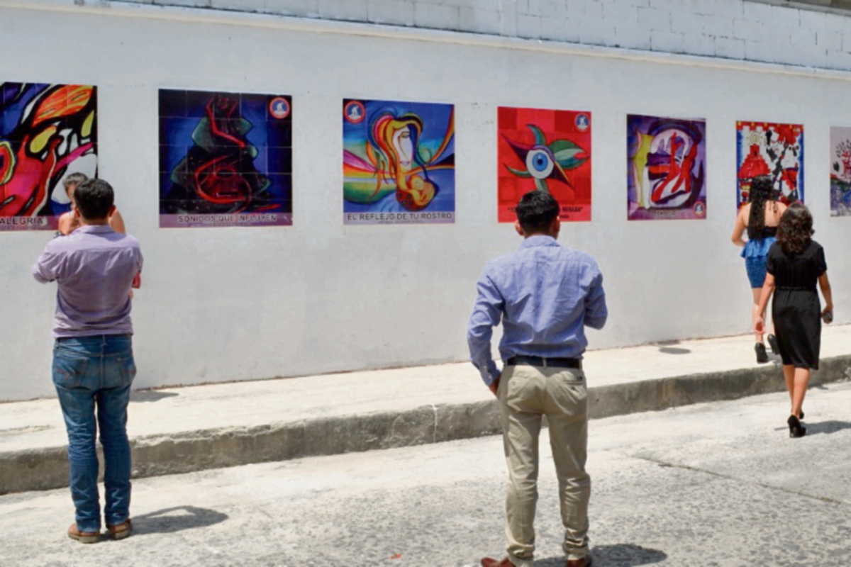 Universitarios aprecian algunas pinturas colocadas en una calle de la ciudad de Retalhuleu.