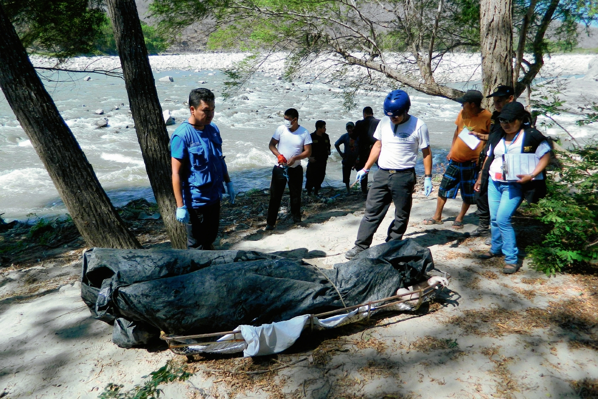 Investigadores observan el cadáver de un hombre que fue localizado en el río Motagua, en Zacapa. (Foto Prensa Libre: Víctor Gómez)