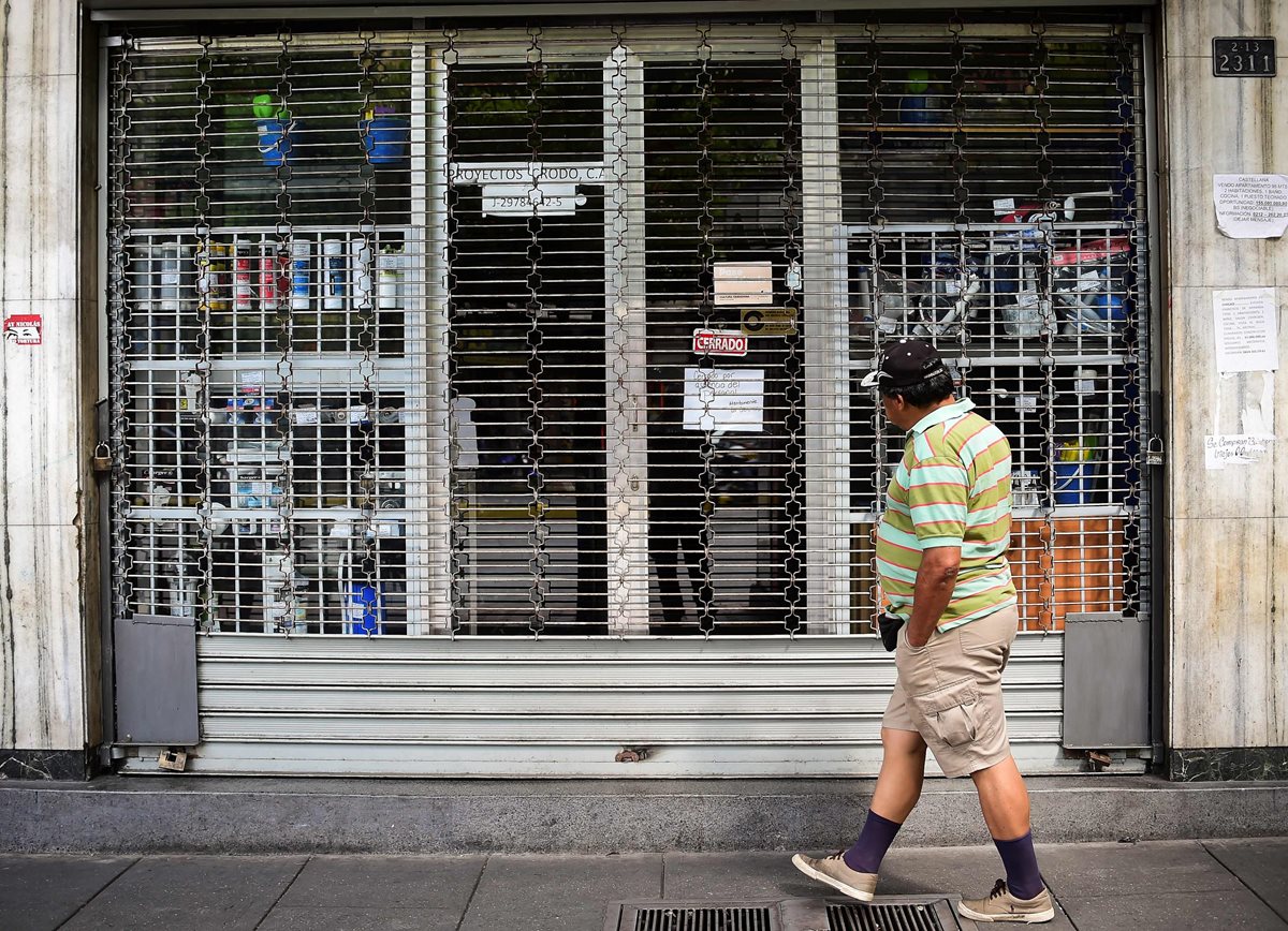 Un venezolano camina frente a un negocio cerrado en Caracas. (Foto Prensa Libre: AFP).