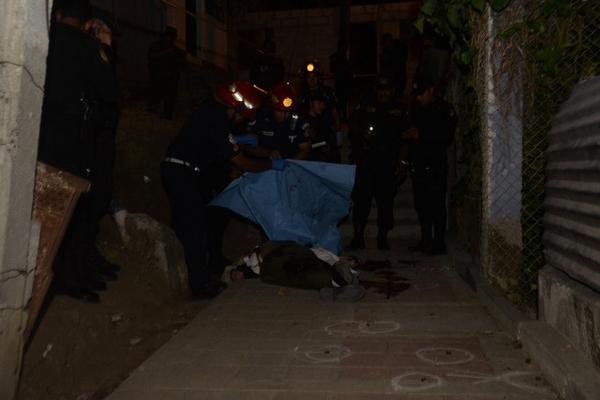 Socorristas de Bomberos Municipales cubren el cadáver de Francisco Oshloj, en el asentamiento La Isla, zona 12 de Villa Nueva. (Foto Prensa Libre: CBM)