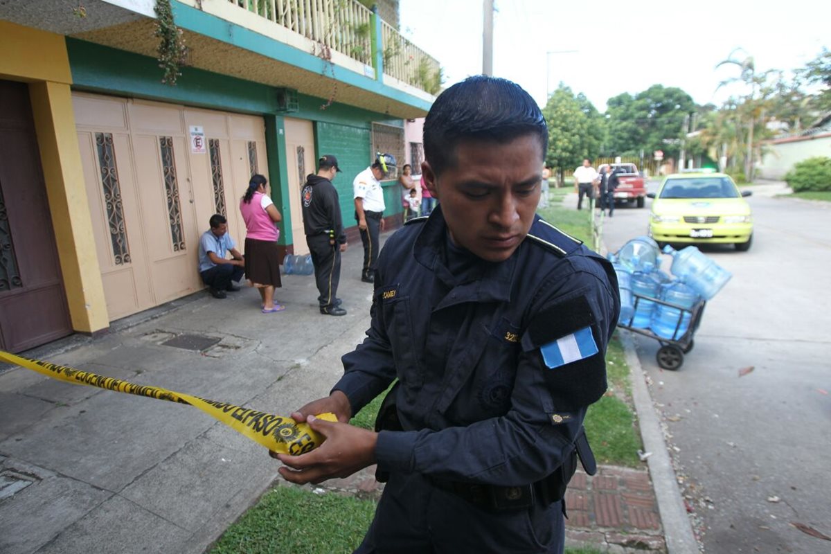 Un policía cierra el paso en el lugar donde quedó el cadáver del trabajador, a un costado de los garrafones de agua que vendía. (Foto Prensa Libre: Érick Ávila)