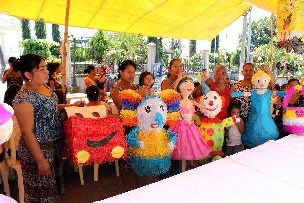 Vecinas que participaron en curso muestran distintos diseños de piñatas elaboradas por ellas.
