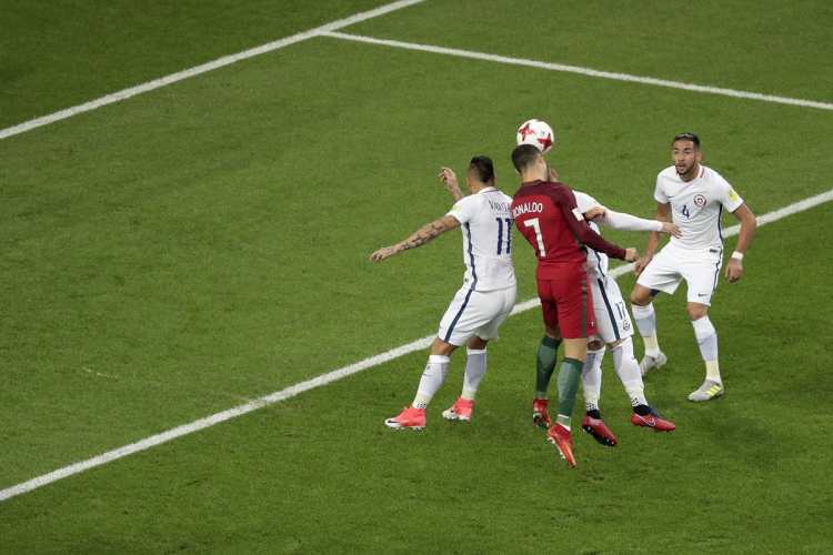 Cristiano Ronaldo cabecea desviado dentro del área en medio de la marca de la defensa chilena.