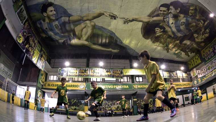 Los niños del Sportivo Pereyra de Barracas juegan bajo el mural de los astros argentinos. (Foto Prensa Libre: AFP)