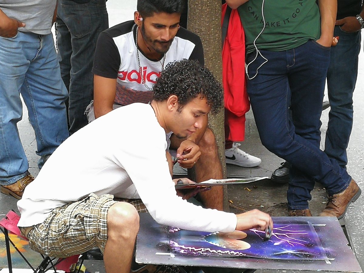 Cristian Sánchez Vigil  observa como  uno de sus compañeros pinta con aerosol, en la Sexta Avenida. (Foto Prensa Libre: César Pérez)