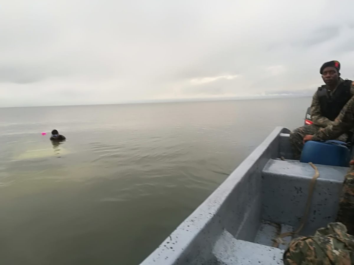 Soldados inspeccionan el lugar del accidente. A un costado el piloto permanece sobre el vehículo hundido en el Lago de Izabal. (Foto Prensa Libre: Dony Stewart).