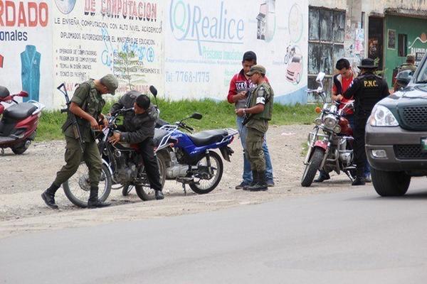 Soldados y  agentes de la PNC solicitan documentos a pilotos de motocicletas, en una calle de la cabecera  de Huehuetenango. (Foto Prensa Libre: Mike Castillo)