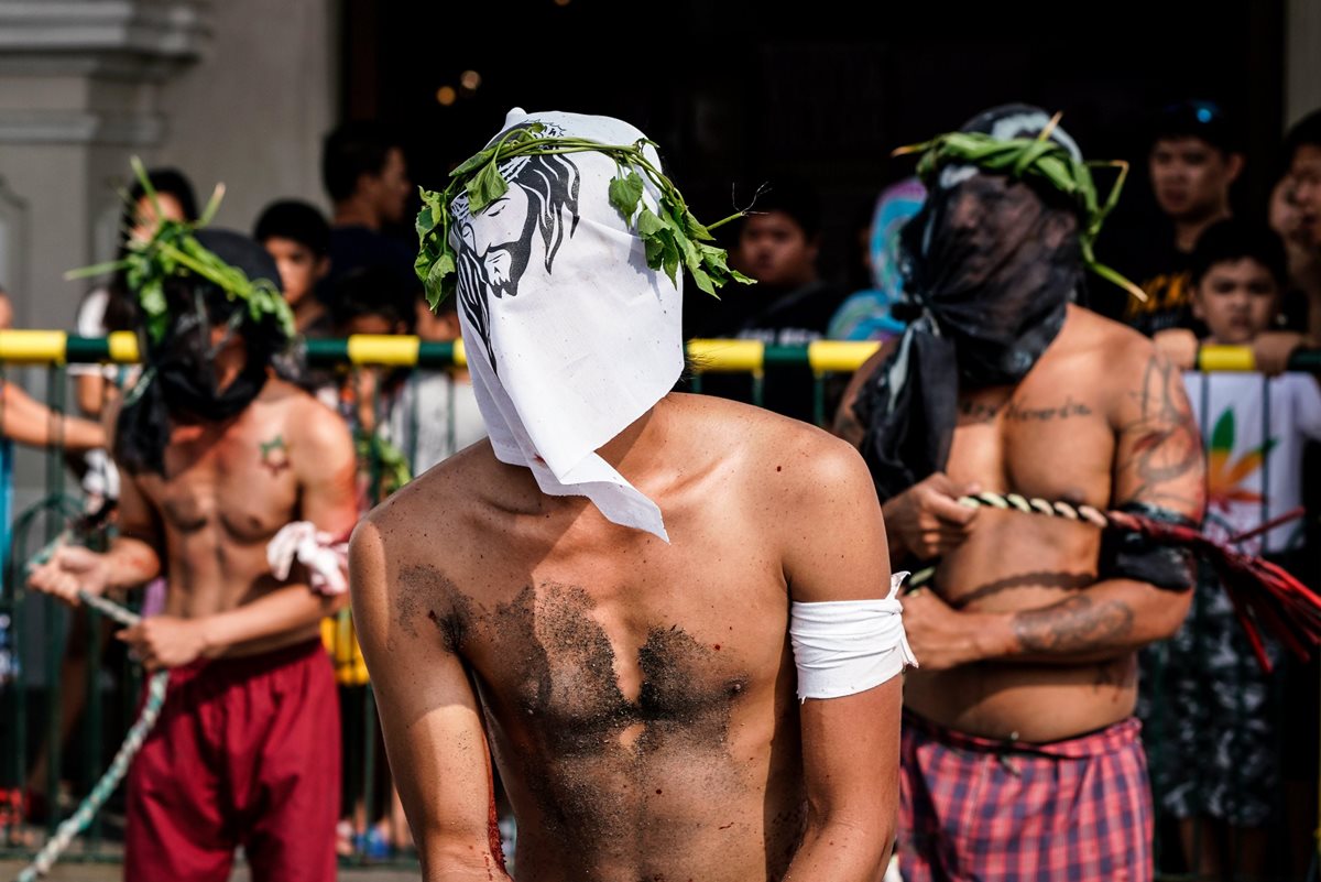 Penitentes se fustigan mientras caminan en procesión hacia una iglesia con el rostro cubierto durante las celebraciones del Jueves Santo en San Pedro Cutud, Filipinas. (Foto Prensa Libre: EFE)