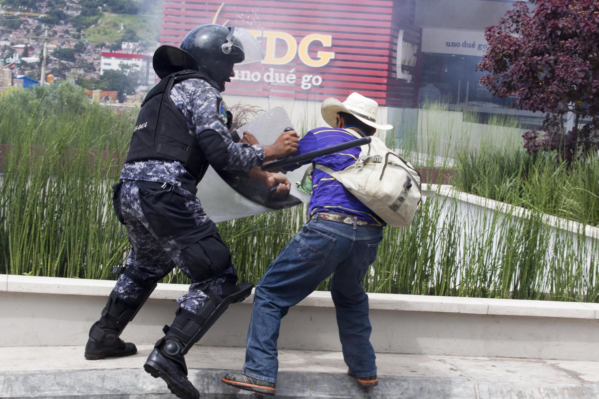 Agente agrede a un campesino lenca, en Honduras. (Foto Prensa Libre: EFE)