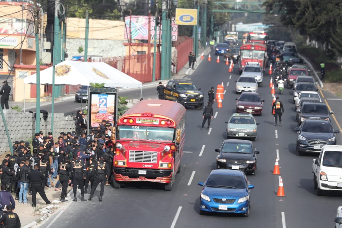 Los pasajeros de autobuses que transitan en las calzadas San Juan y Roosevelt descienden de las unidades para ser revisados por agentes de la PNC. (Foto Prensa Libre: Érick Ávila)