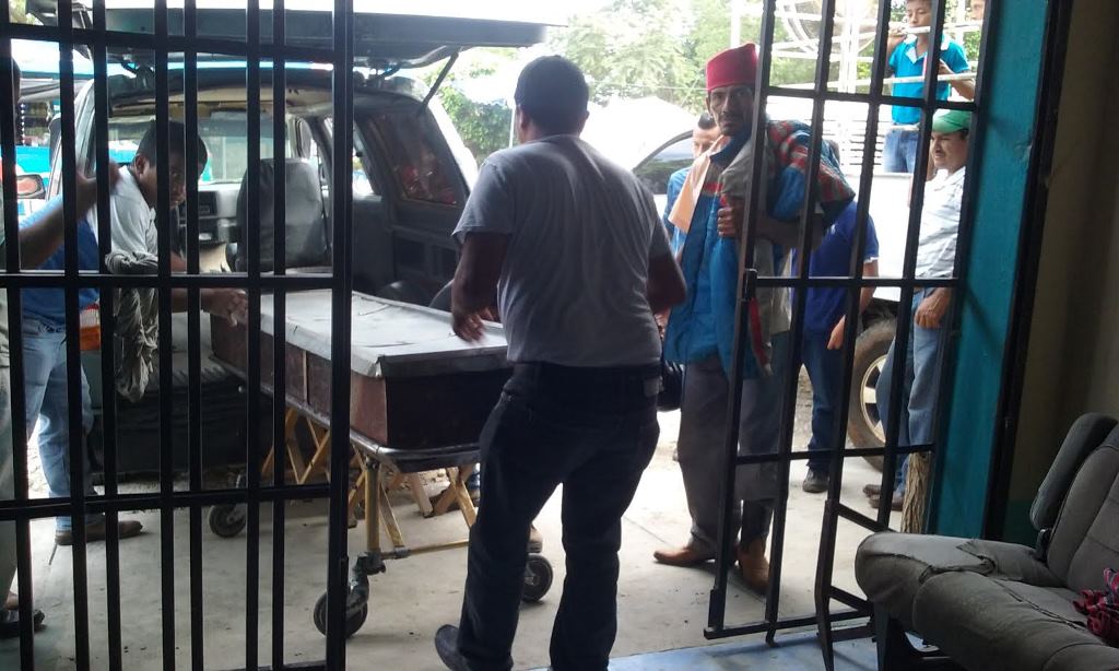 Empleados de una funeraria de San Benito trasladan el cadáver de Miguel Suchité Hernández. (Foto Prensa Libre: Rigoberto Escobar).