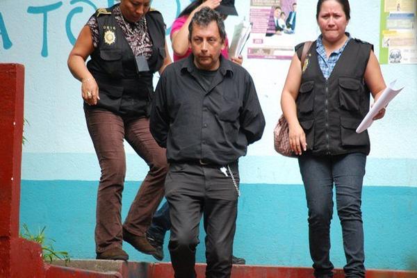 Raúl Arturo  Fuentes Villela, de 56 años, originario de la  capital y con residencia en Panajachel, es custodiado por autoridades del MP. (Foto Prensa Libre: Ángel Julajuj)