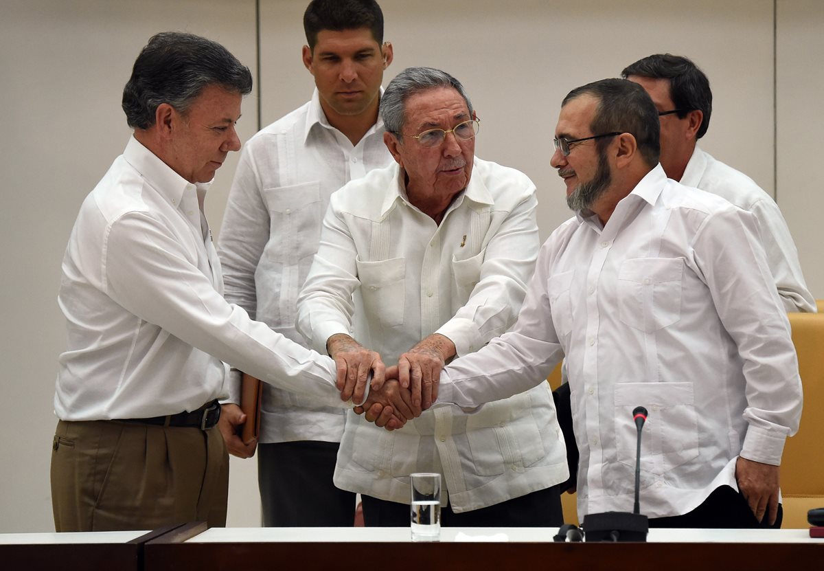 Raúl Castro (centro) propició un apretón de manos entre Santos y Timochenko.(Foto Prensa Libre: AFP).
