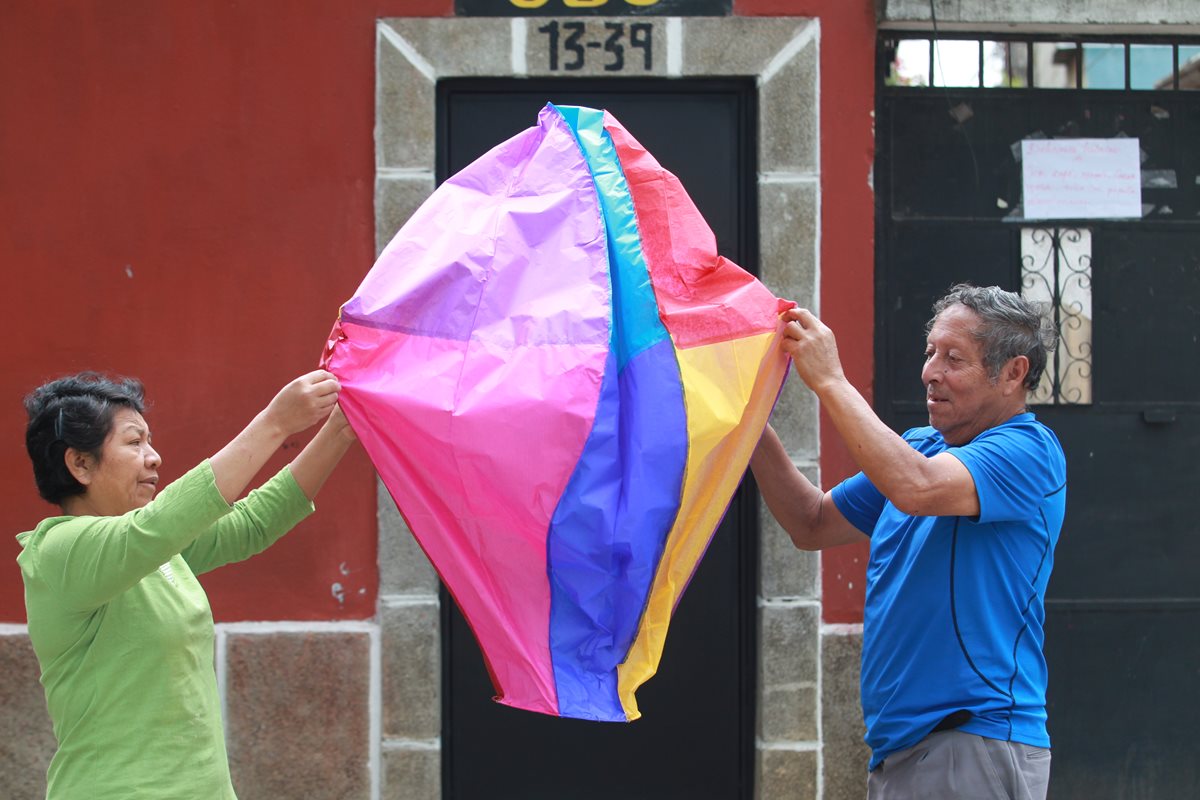 Con ayuda de su esposa, Marco Antonio Chacón extiende uno de los globos más pequeños que elabora. (Foto Prensa Libre: Estuardo Paredes)