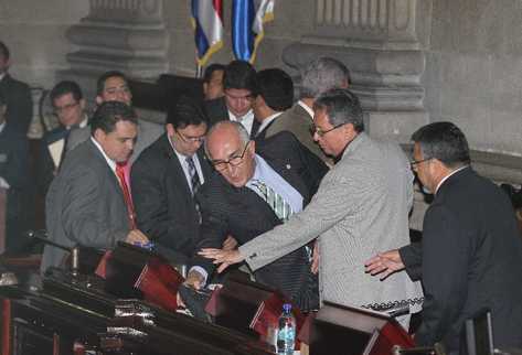 El diputado Mario Taracena  se inclina para agarrar un objeto que pretendía lanzar a Gudy Rivera, luego de  una  discusión.