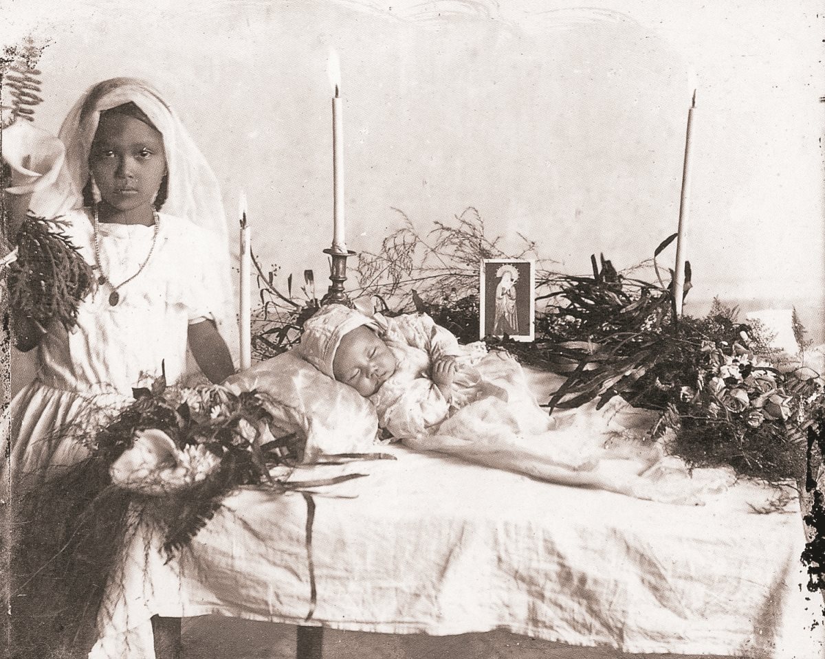 Niño yacente, acompañado de su hermana. La fotografía fue tomada en Antigua Guatemala, en un altar dedicado a la Virgen de Dolores, a finales del siglo XIX e inicios del XX.