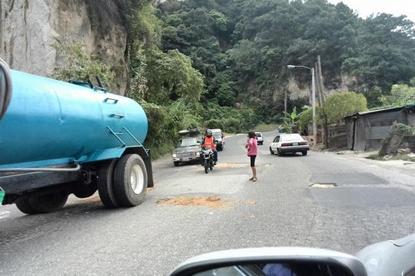 Niños arriesgan la vida para pedir dinero por tapar hoyos. (Foto Prensa Libre)