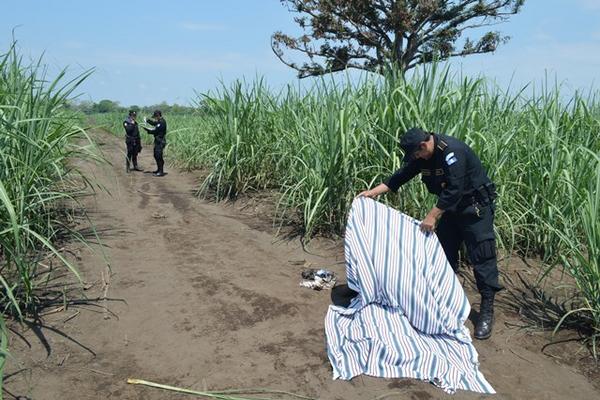 Un agente de la PNC cubre el cuerpo de Elí Noel Gamboa Zapet, en La Gomera, Escuintla. (Foto Prensa Libre: Enrique Paredes)