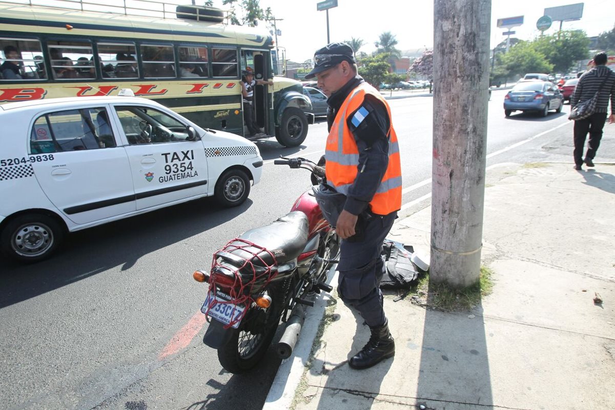 Agente de la PNC revisa una de las motocicletas usadas para cometer asalto en la calzada Roosevelt, zona 11. (Foto Prensa Libre: Erick Ávila)