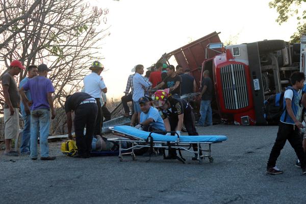 Bomberos trasladaran a uno de los heridos, al fondo el camión volcado. (foto Prensa Libre: Hugo Oliva)<br _mce_bogus="1"/>