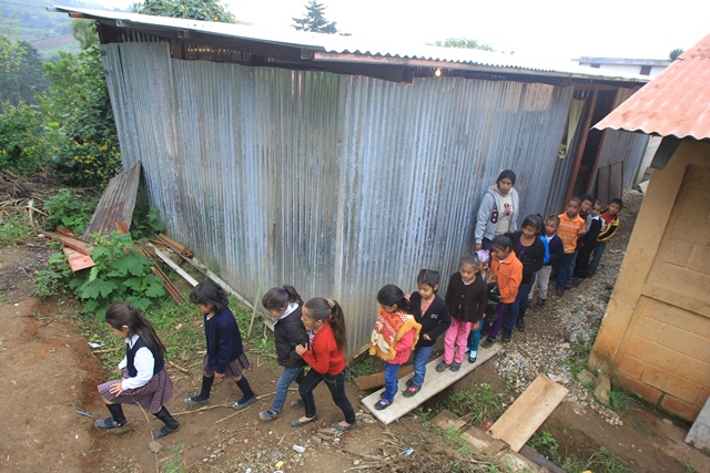 Estudiantes salen de un aula construida con láminas y madera. (Foto Prensa Libre: Esbin García)