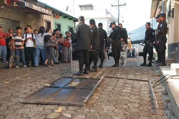 Agentes de la PNC custodian uno de los inmuebles atacados por pobladores de San Lucas Tolimán,  descontentos con la reelección del alcalde.