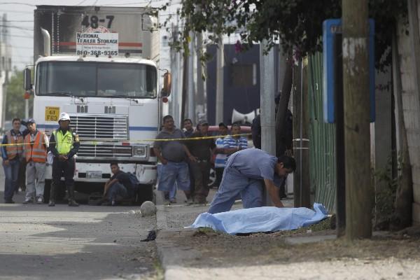 Una persona cubre el cuerpo del mecánico Sergio Barillas, quien fue atacado  junto a sus compañeros cuando jugaban futbol en una calle de la zona 12.