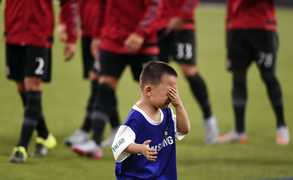 Un pequeño recoge pelotas llora tras fotografiarse con los jugadores del Real Madrid antes del encuentro amistoso. (Foto Prensa Libre: AFP)