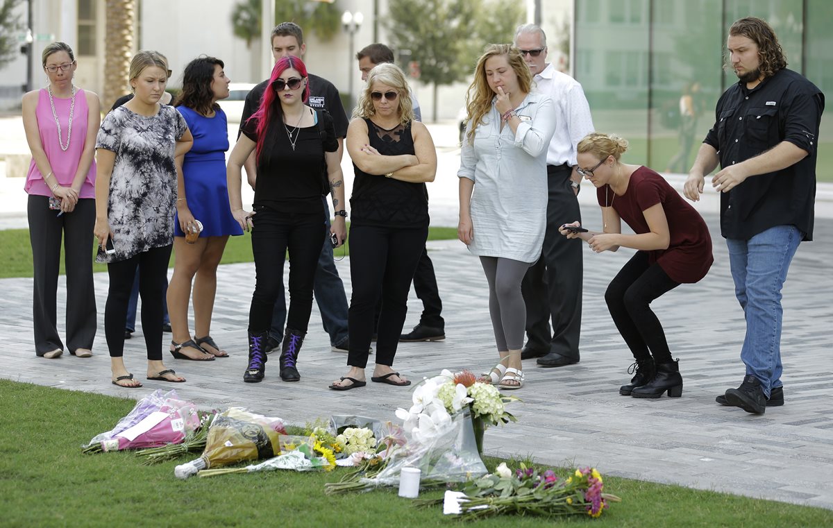 Un grupo de personas coloca flores en un lugar cercano a la discoteca Pulse, donde el domingo en la madrugada ocurrió la masacre. (Foto Prensa Libre: AP).