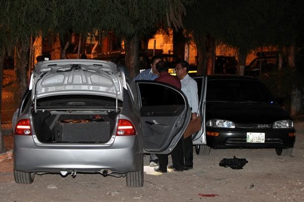 Agentes buscan evidencias en los vehículos decomisados. (Foto Prensa Libre)