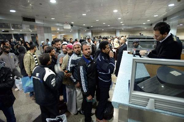 Cientos de egipcios hacen fila ante funcionarios de migración, a su llegada al aeropuerto de El Cairo. (Foto Prensa Libre: EFE)