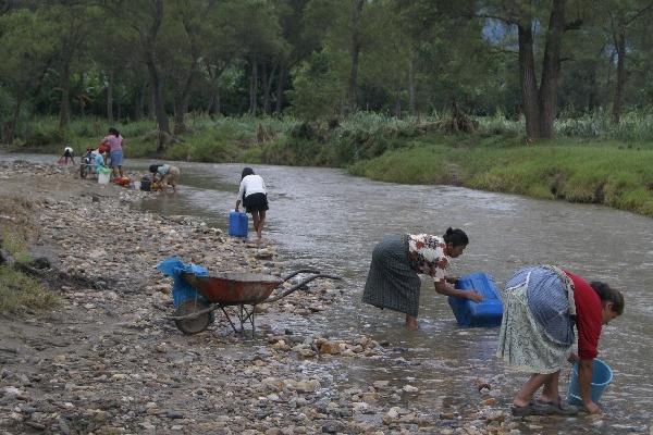 mujeres se abastecen en  río contaminado.