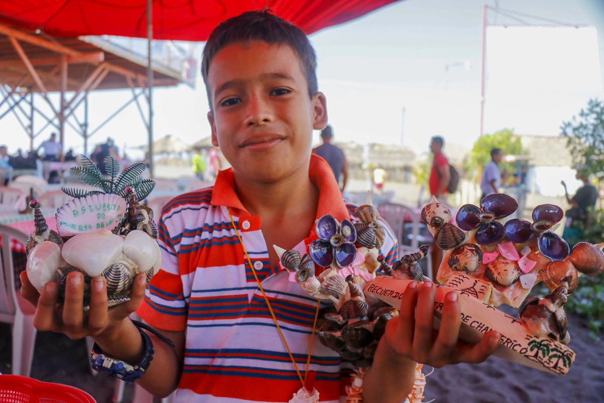 Niño muestra algunas de las artesanías que los visitantes encontrarán en Champerico. (Foto Prensa Libre: Rolando Miranda).
