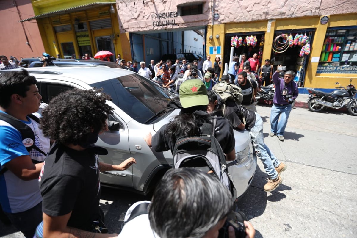 Uno de los manifestantes se subió al bumper del vehículo para evitar que el ministro de Salud huyera del lugar. (Foto Prensa Libre: Esbin García)