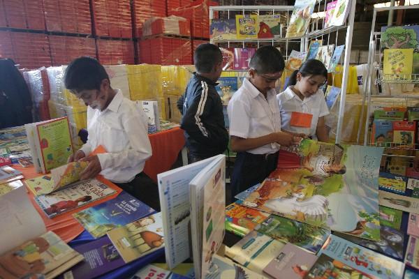 Niños observan, en una bodega del Mineduc, parte de los 4.5 millones de libros que serán distribuidos a 20 mil estudiantes en el país.