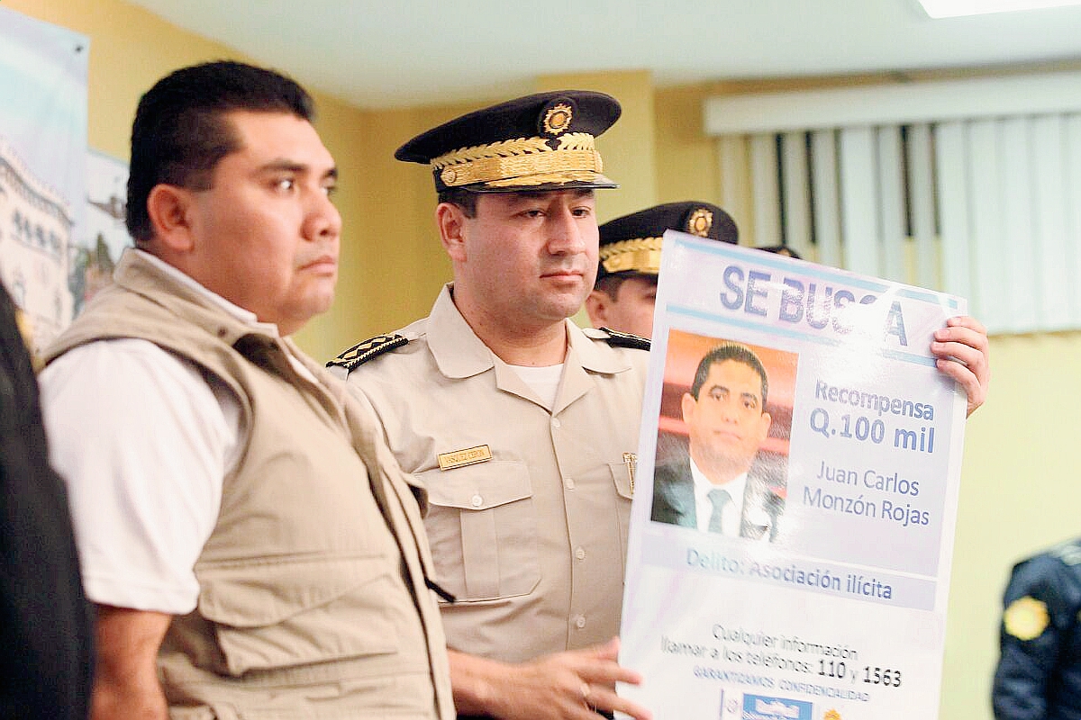 Elmer Sosa (izquierda), viceministro de Gobernación, entrega un afiche al director de la PNC, Walter René Velásquez Cerón, con la foto de Juan Carlos Monzón. (Fotografía Prensa Libre: Alvaro Interiano).