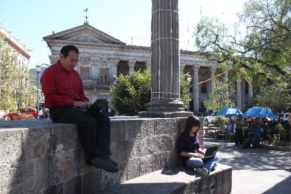 Un hombre  y una jovencita  hacen uso del internet inalámbrico en el parque Central  de Xelajú.