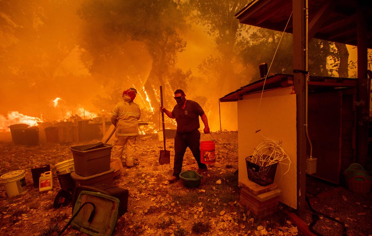 Un propietario de una vivienda busca agua para controlar el fuego en el complejo de Mendocino,California. (AFP).