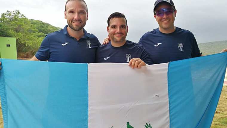 Los hermanos Enrique y Hebert Brol, junto a Pablo Duarte posan con la bandera tras haber ganado la medalla de oro en doble foso en los Juegos de Barranquilla. (Foto Prensa Libre: Carlos Vicente)